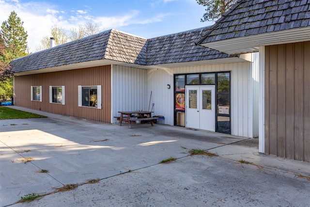 rear view of property featuring a patio area and mansard roof