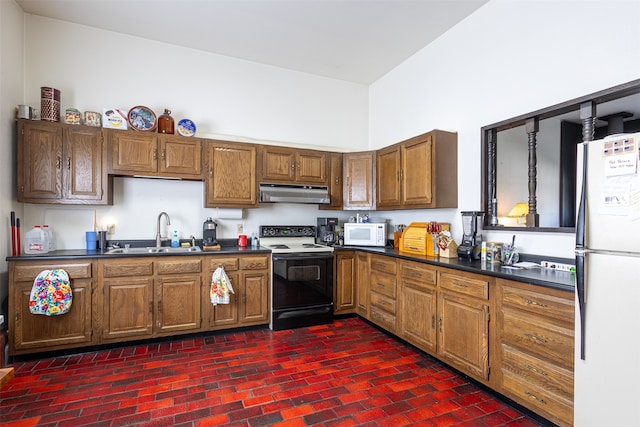 kitchen with brown cabinets, dark countertops, a sink, white appliances, and under cabinet range hood