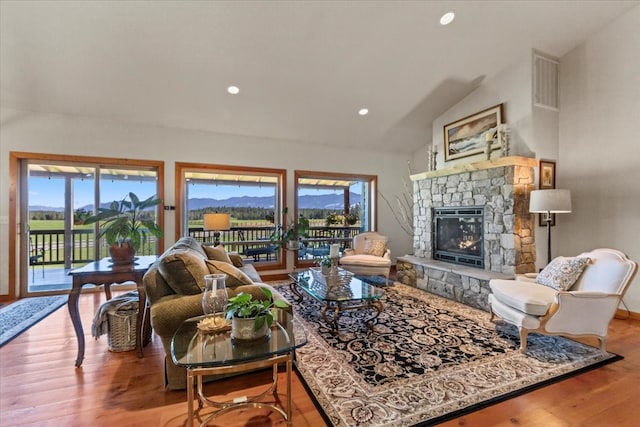 living room featuring a mountain view, vaulted ceiling, a fireplace, and light hardwood / wood-style flooring