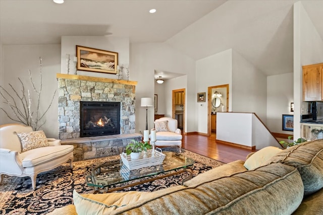 living room featuring a stone fireplace, hardwood / wood-style floors, and high vaulted ceiling