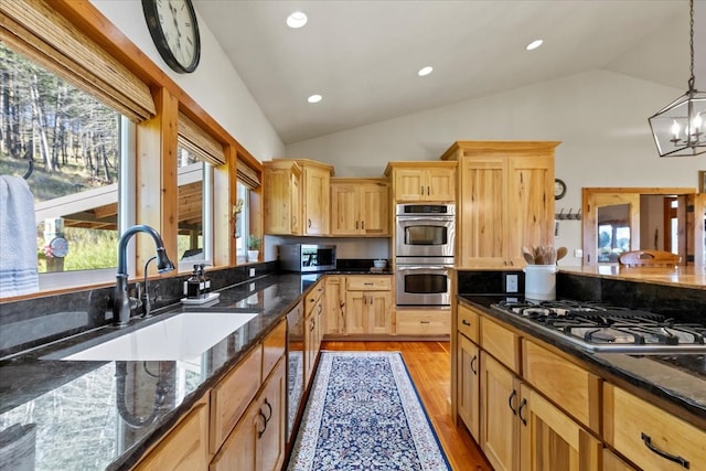 kitchen with appliances with stainless steel finishes, decorative light fixtures, vaulted ceiling, and plenty of natural light