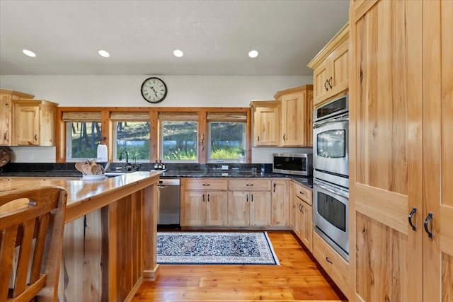 kitchen with light brown cabinetry, light wood-type flooring, stainless steel appliances, and sink