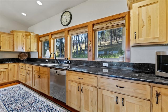 kitchen with dishwasher, dark stone countertops, lofted ceiling, and a wealth of natural light