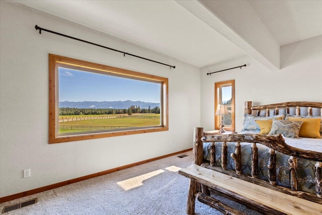 bedroom with beam ceiling, a mountain view, and carpet floors