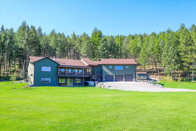 back of property with a wooden deck, a yard, and a garage