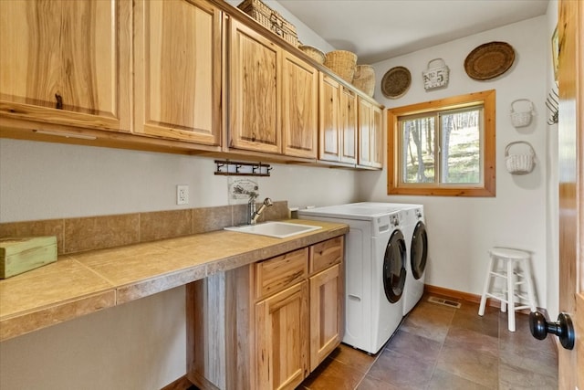 laundry area featuring separate washer and dryer, sink, and cabinets