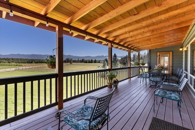 wooden terrace with a mountain view, a yard, and a rural view