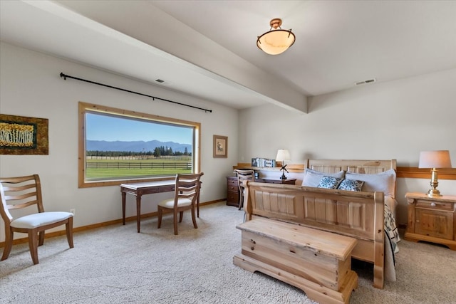 bedroom with a mountain view, light colored carpet, and beamed ceiling