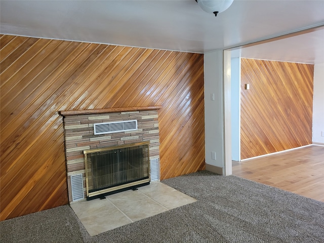 interior space featuring a stone fireplace, wooden walls, and light wood-type flooring