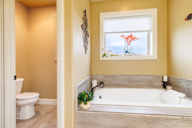 bathroom featuring hardwood / wood-style floors, a relaxing tiled tub, and toilet