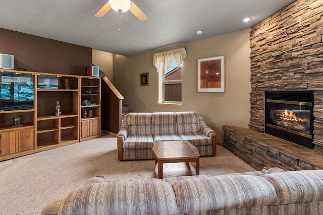 living room with carpet floors, a stone fireplace, and ceiling fan