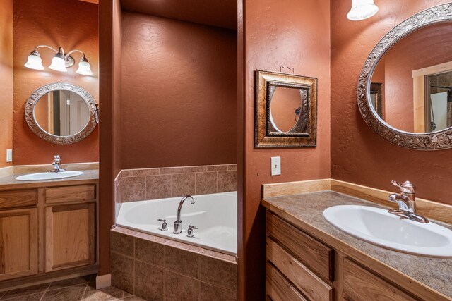 bathroom featuring a relaxing tiled tub, tile patterned flooring, and vanity