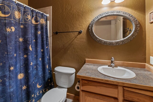 bathroom with walk in shower, vanity, and toilet