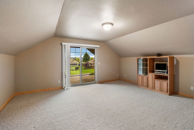 additional living space with a textured ceiling, carpet, and lofted ceiling