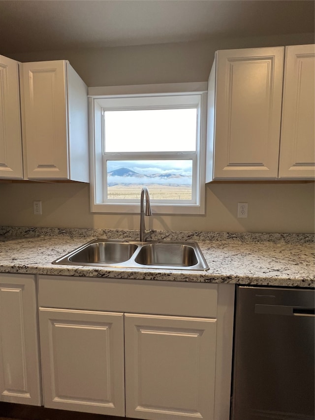 kitchen with white cabinets, stainless steel dishwasher, sink, and light stone counters