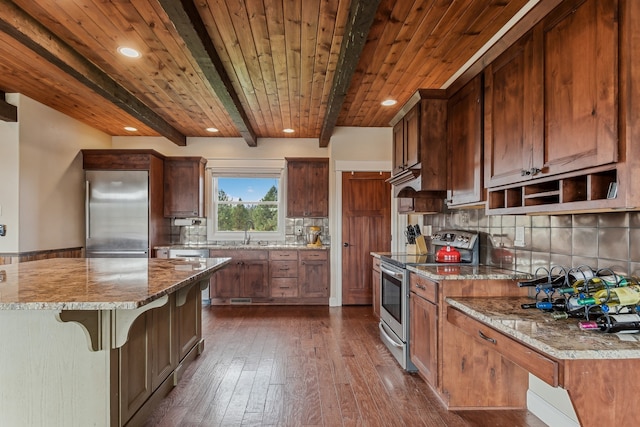 kitchen with stainless steel appliances, a kitchen island, light stone counters, and decorative backsplash