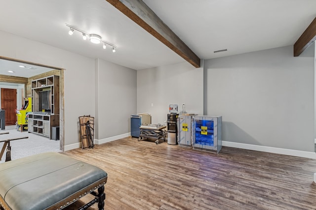 interior space featuring hardwood / wood-style flooring, track lighting, and beam ceiling