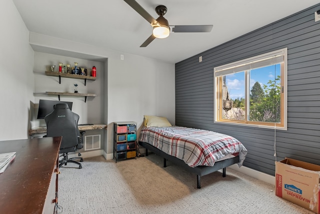 bedroom featuring ceiling fan and wooden walls