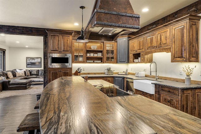 2870 US Highway 93 W, Whitefish, MT 59937 - kitchen with stainless steel microwave, premium range hood, decorative light fixtures, recessed lighting, and glass insert cabinets