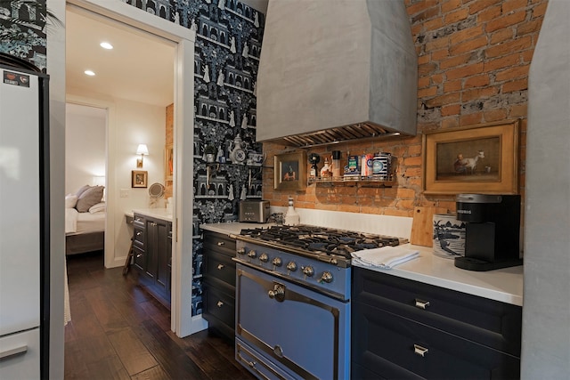 kitchen featuring wall chimney exhaust hood, dark wood-type flooring, white fridge, and high end range