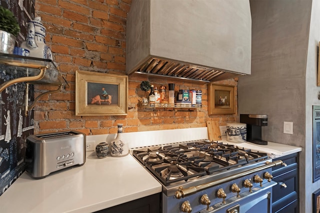 kitchen with brick wall, stainless steel range, and custom exhaust hood