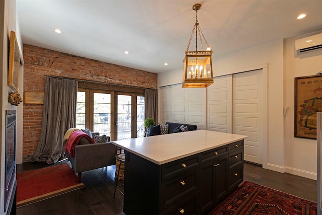 kitchen with a kitchen breakfast bar, dark wood-type flooring, a kitchen island, an AC wall unit, and pendant lighting