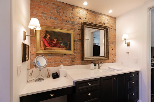 bathroom featuring brick wall and vanity