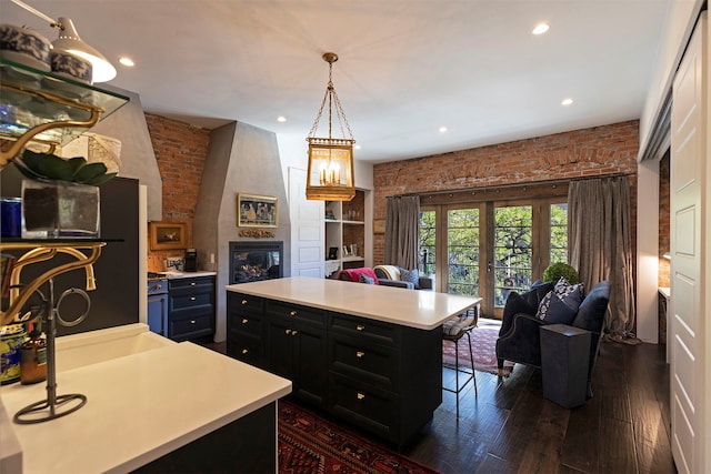 kitchen with dark hardwood / wood-style floors, a breakfast bar area, hanging light fixtures, a kitchen island, and a large fireplace