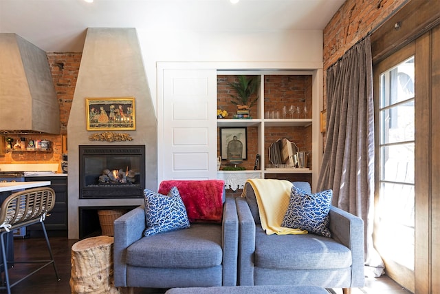 living area with wood-type flooring, a fireplace, and brick wall