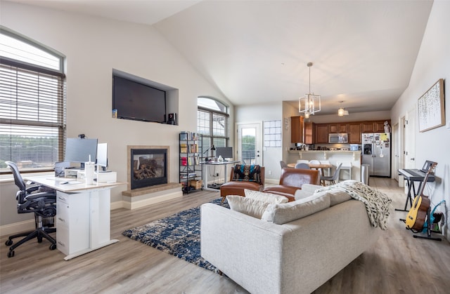 living room with lofted ceiling, a chandelier, and light hardwood / wood-style floors