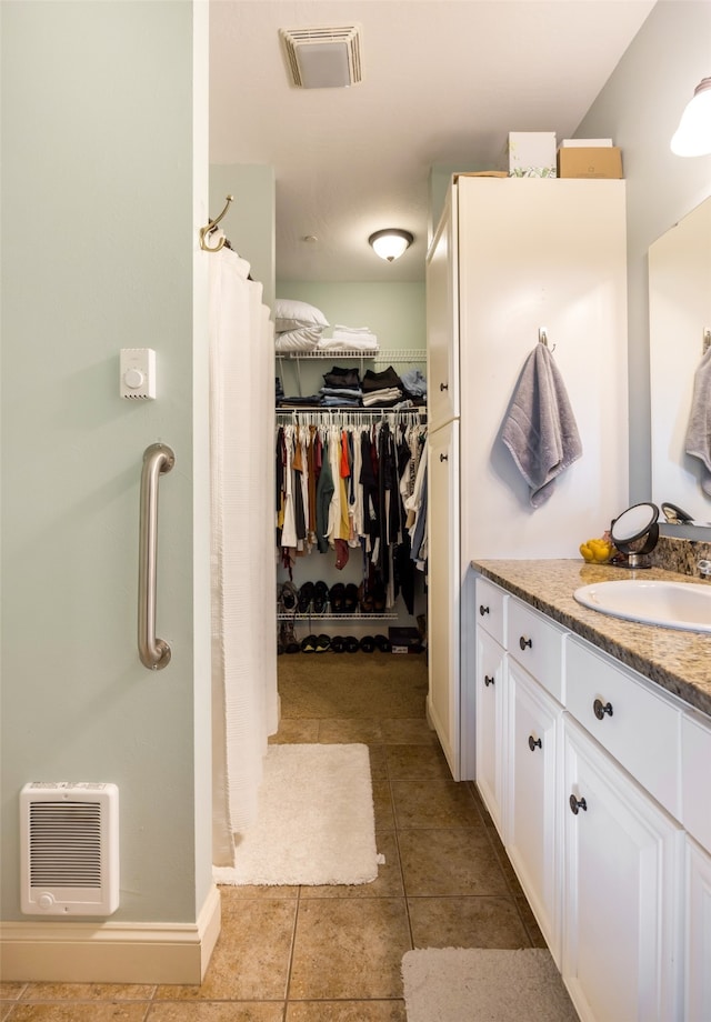 bathroom with heating unit, tile patterned floors, walk in shower, and vanity