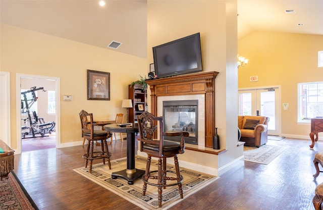 interior space with wood-type flooring, a fireplace, high vaulted ceiling, an inviting chandelier, and french doors