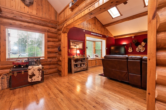 living room featuring rustic walls, light hardwood / wood-style flooring, a skylight, and high vaulted ceiling