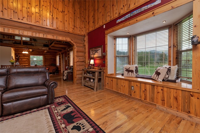 living room featuring light wood-type flooring, a high ceiling, and log walls