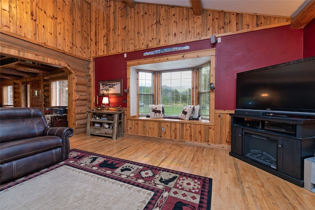 living room with wooden walls, beam ceiling, hardwood / wood-style floors, and high vaulted ceiling