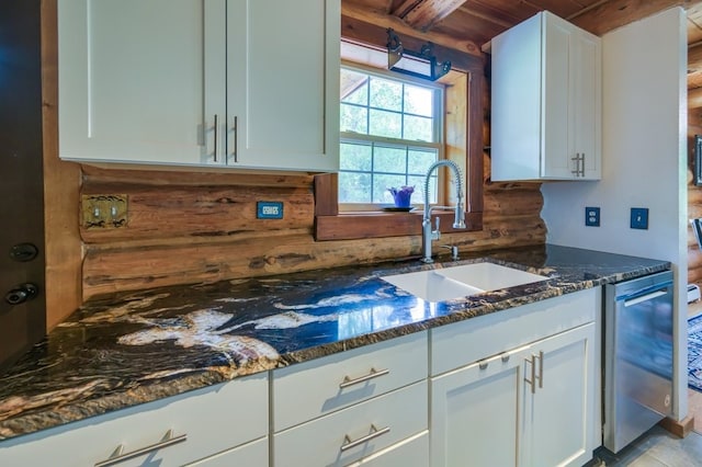 kitchen featuring wood ceiling, wood walls, sink, white cabinetry, and dark stone counters