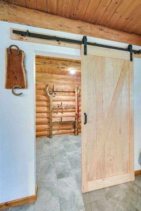 interior space featuring wood ceiling, log walls, and a barn door