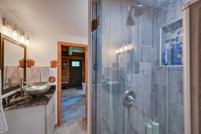 bathroom with a tile shower and vanity