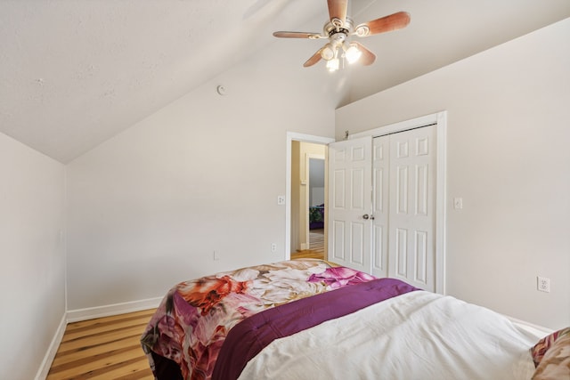 bedroom with lofted ceiling, hardwood / wood-style floors, ceiling fan, and a closet