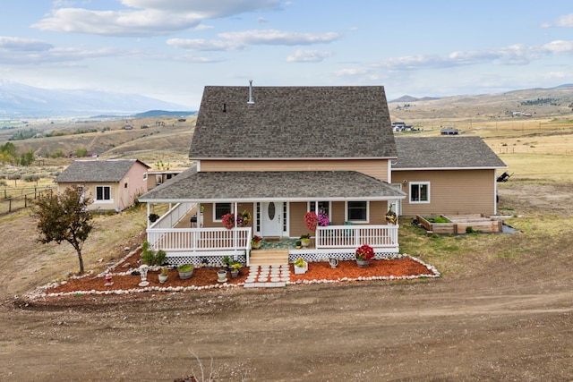 country-style home with a mountain view, covered porch, and a rural view