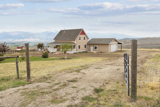 view of front of property featuring a mountain view, a garage, covered porch, and a rural view