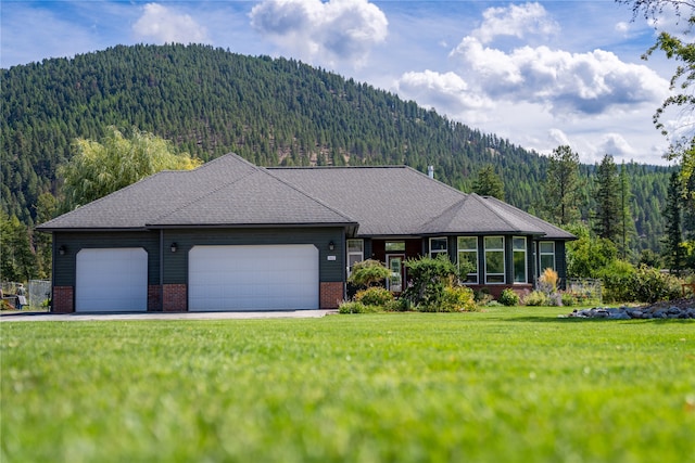 ranch-style house featuring a mountain view, a garage, and a front lawn