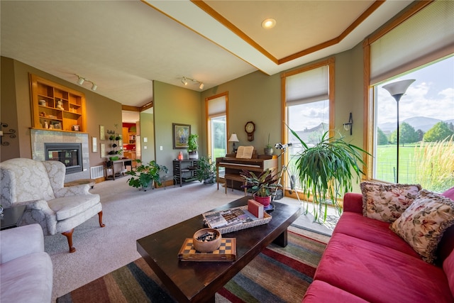 living room with a tiled fireplace, track lighting, and carpet flooring