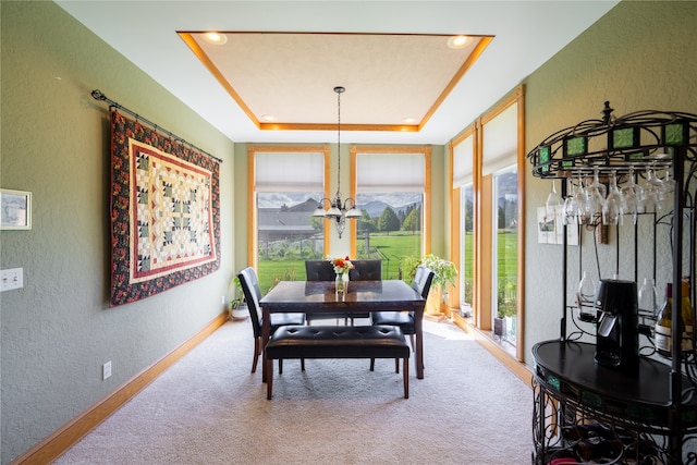 dining space with a notable chandelier, a tray ceiling, and carpet flooring