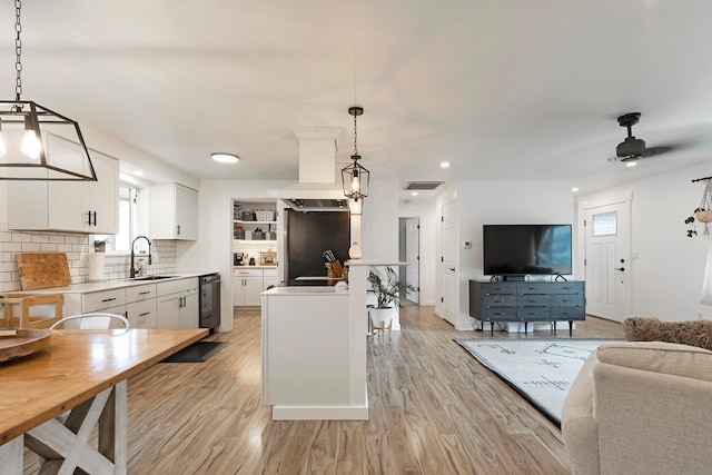 kitchen featuring white cabinets, decorative light fixtures, light hardwood / wood-style floors, and sink