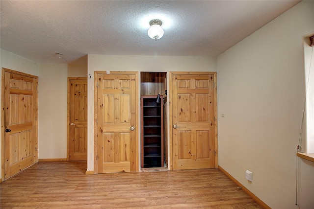 72878 Lemlama Trl, Arlee, MT 59821 - unfurnished bedroom with baseboards, light wood-style flooring, and a textured ceiling
