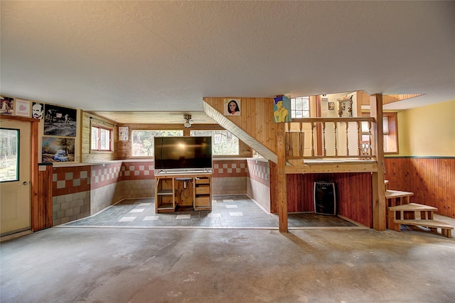 72878 Lemlama Trl, Arlee, MT 59821 - unfurnished living room with a textured ceiling, unfinished concrete floors, wooden walls, and wainscoting