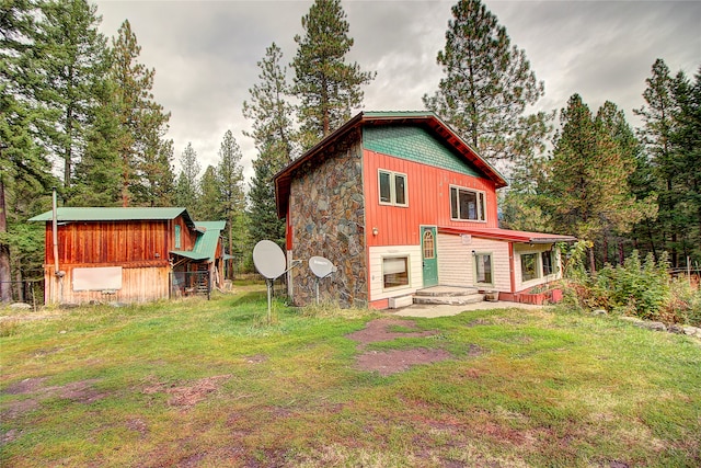 rear view of house featuring a lawn and an outbuilding