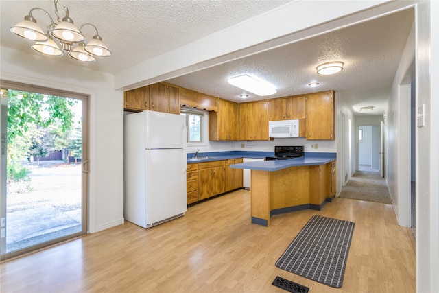 kitchen featuring white appliances, light hardwood / wood-style flooring, kitchen peninsula, and a wealth of natural light