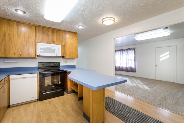 kitchen featuring a kitchen breakfast bar, white appliances, kitchen peninsula, light wood-type flooring, and a textured ceiling